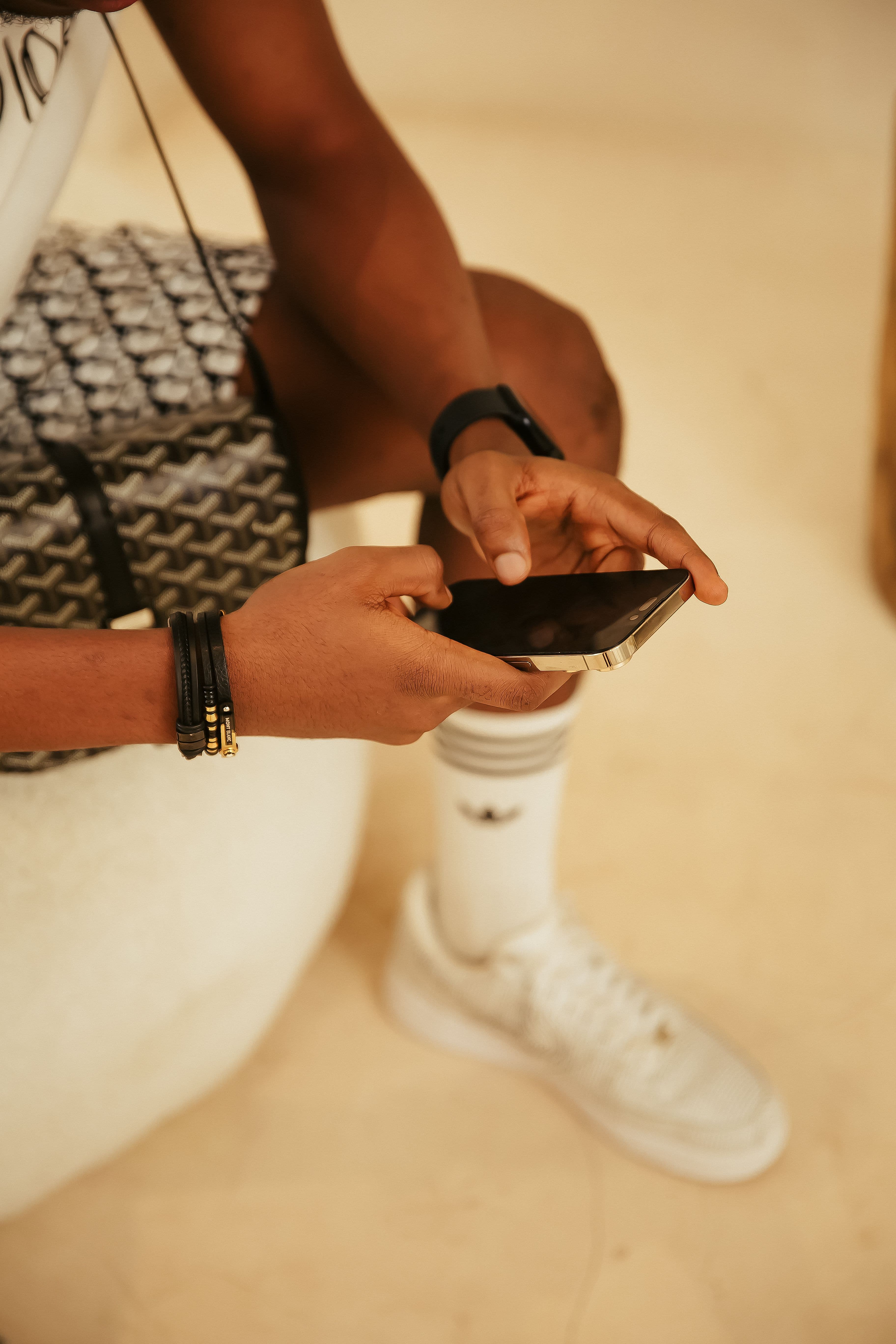Mains tenant un smartphone — sac Goyard, bracelets premium, élégance contemporaine